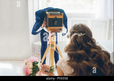 Funny photo concept. The groom photographs the bride on a vintage camera Stock Photo