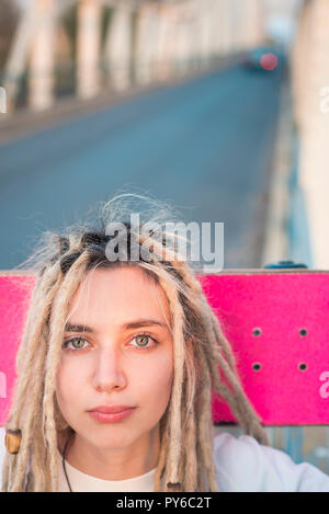 Beautiful young woman with pink skateboard portrait Stock Photo