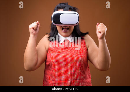 Excited overweight Asian woman using virtual reality VR glasses Stock Photo