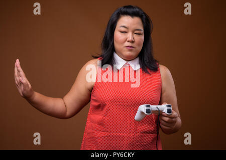 Beautiful overweight Asian woman playing video games using game controller
