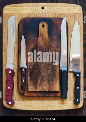 Wooden cutting boards and various kitchen knives. Top view Stock Photo