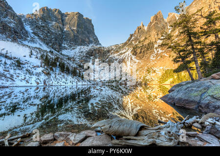 Interesting driftwood on the shores, with mountains mirrored in Emerald Lake in Rocky Mountain National Park. Stock Photo