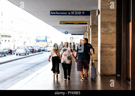 Rome, Italy - September 4, 2018: Tourists in city with entrance to Termini rail station, people with luggage walking
