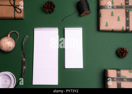 Above view of two unwritten notebooks on a green background, surrounded by Christmas gifts and decorations. Stock Photo