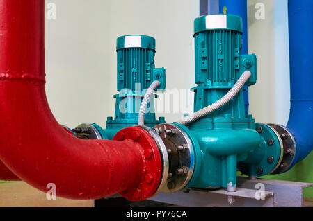 Two vertical engine painted blue with pumps connected to pipes painted red and blue. Stock Photo