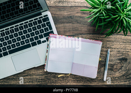 open pocket calendar or personal organizer on rustic wooden table with laptop and succulent plant Stock Photo