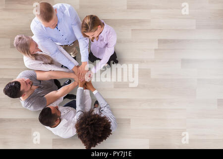 High Angle View Of Businesspeople Stacking Their Hands In Office Stock Photo