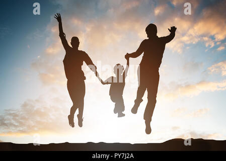 Silhouette Of Family Jumping In Mid-air Against Dramatic Sky Stock Photo