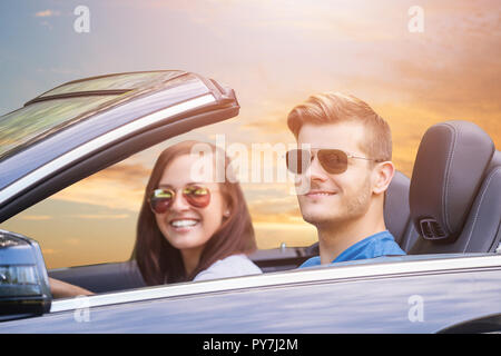 Young Couple Wearing Sunglasses Enjoying Ride In A Car Stock Photo