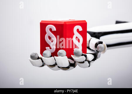 Robotic Hand Holding Red Cubic Block With Paragraph Symbol On Gray Background Stock Photo