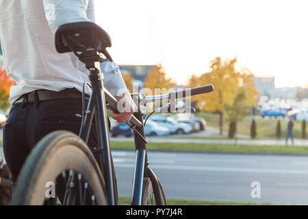 Businessman on a bike. Business man leaving his work. From back. Stock Photo