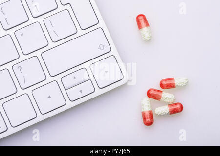 A bunch of pills next to the computer keyboard Stock Photo - Alamy