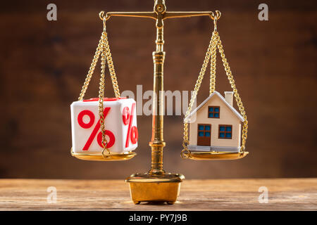 Golden Justice Scale Showing Balance Between Percentage Sign Block And House Model On Wooden Desk Stock Photo