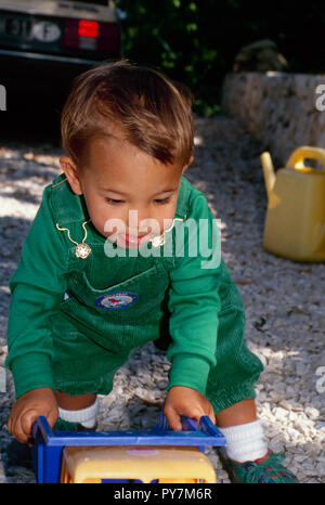 Toddler, Afghan American, with toy truck playing in yard, Switzerland, CH Stock Photo