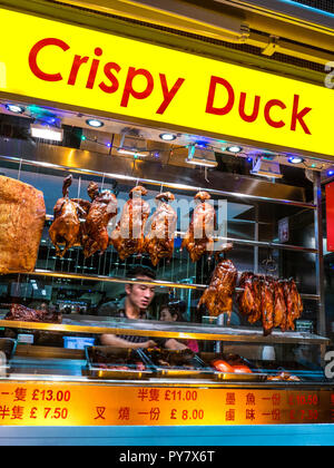 CRISPY DUCK WINDOW DISPLAY CHINATOWN Chef arranging duck & pork hanging air drying in Chinese restaurant Gerrard Street Chinatown Soho London UK Stock Photo