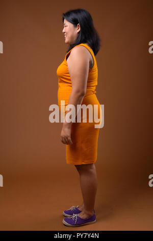 Full length profile view of beautiful overweight Asian woman smiling Stock Photo