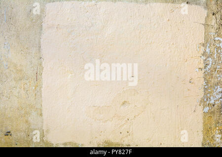 Sand color rough concrete wall with a cracks and a painted white square. Blank painted square on urban concrete wall as copy space Stock Photo