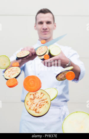 Young chef slicing vegetables towards camera Stock Photo
