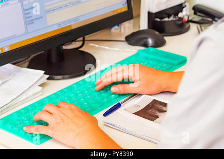Female hands type on blue silicon keyboard close Stock Photo