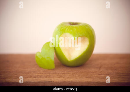 A green apple, with a heart shaped bite taken out of it. Stock Photo