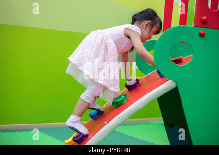 Asian Chinese little Girl playing at mini rock climbing wall at Indoor Playground Stock Photo