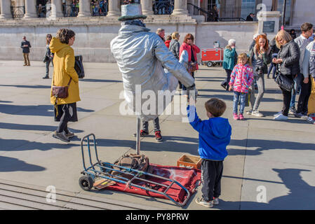 Man painted as a silver human statue in Trafalgar Square, London, England, UK. Stock Photo