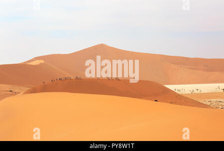 Namibia desert -  tourists walking the crest of sand dunes in the Namib desert at Sossusvlei, Namibia Africa Stock Photo