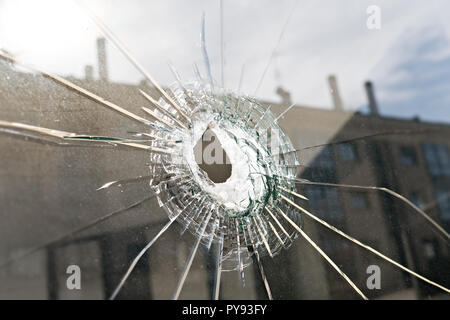 Vandalism or violence concept. Broken glass with hole Stock Photo