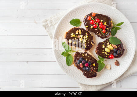 Sandwiches with chocolate paste, pistachio nuts and fresh berries on a plate Stock Photo