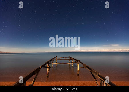 Ancient pier and stars at the twilight in Issyk Kul Lake, Kyrgyzstan Stock Photo
