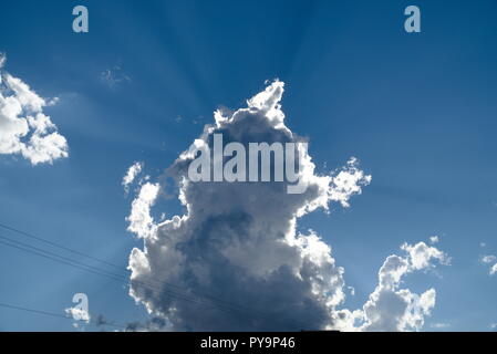 The Sun shines from behind a white cloud. In the bottom-left there are telephone wires. Stock Photo