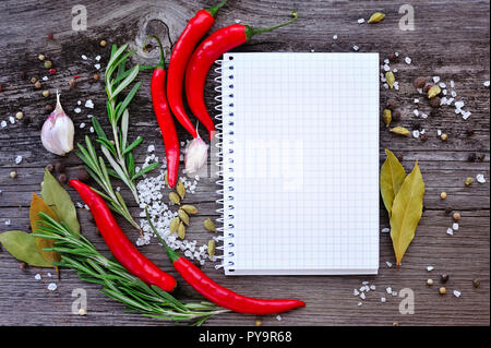 Vegetables and seasonings with open notebook for recipes on a wooden background Stock Photo