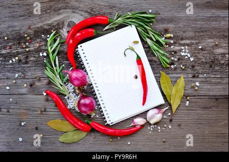 Vegetables and seasonings with open notebook for recipes on a wooden background Stock Photo