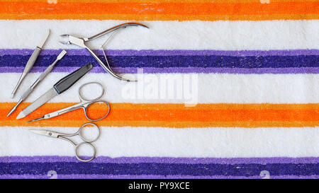A set of tools for manicure and pedicure, composed of  scissors, clipper and nail file on a striped towel Stock Photo