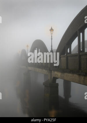 Street lamps glow through the mist on a foggy morning on Dee Bridge over the River Dee, Kirkcudbright, Dumfries and Galloway, SW Scotland. The scene is mysterious and murky Stock Photo