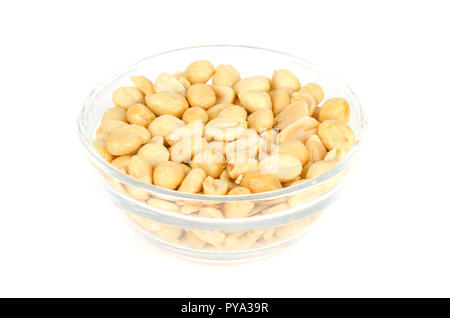 Roasted and salted peanuts in glass bowl. Shelled Arachis hypogaea, also called groundnut or goober, used as a snack. Isolated macro food photo. Stock Photo
