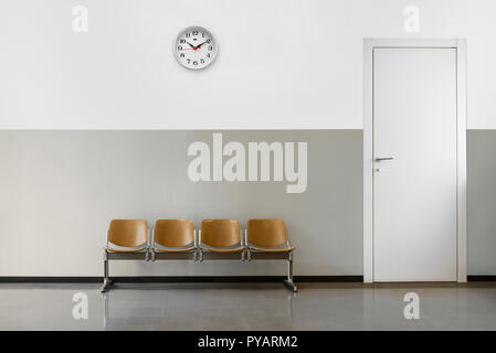 empty waiting room with chairs, clock on wall and door. Stock Photo