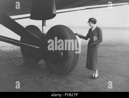 Airplane in the 1930s. A well dressed young woman looks small when comparing her size to the giant wheels on the landing gear to this german Junker G38 aircraft. It was used between Berlin and London from July 1 1931 and was at that time the largest four engined passenger aircraft, with 34 passengers and seven crew members. Stock Photo