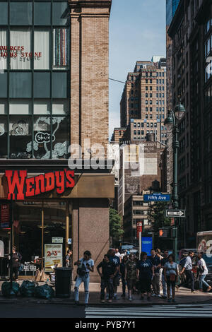New York, USA - May 29, 2018: People waiting to cross Fifth Avenue, New York on a zebra crossing next to Wendy's restaurant. Wendy's is a famous Ameri Stock Photo
