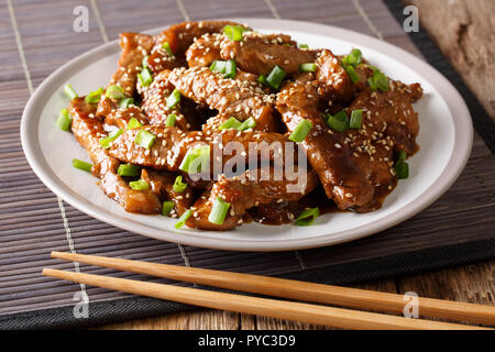 Asian style beef in teriyaki sauce with sesame and green onions closeup on a plate on the table. horizontal Stock Photo