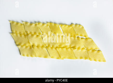 Dry Italian pasta called pantacce  on a white background ,rhombus -shaped pasta with wavy edge ,funny composition , studio shot , top view Stock Photo