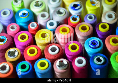 A lot of sewing colored thread on a white table. The view from the top. Stock Photo