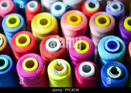 Colored thread for sewing. Threads in spools tape measure, needle bar, needle and scissors on a white background. Stock Photo