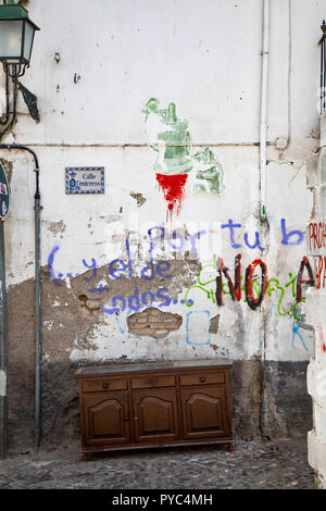 Graffiti on crumbling wall in old street in Granada, Spain with sideboard cupboard. Stock Photo