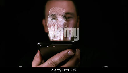 Male holding a digital device with a 3D hologram of a copy of his face. Facial recognition and identity concept Stock Photo