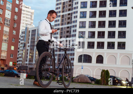 Handsome businessman with bike using a smart phone Stock Photo