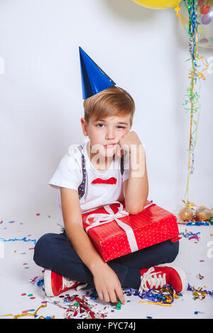 Portrait of a sad cute little kid holding gift box and looking at camera Stock Photo