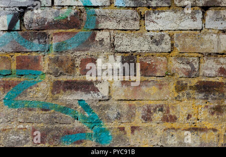 Old red brick wall covered with rests of old white paint and with graffiti of a blue arrow, with space for text on the side. Background, copy space Stock Photo