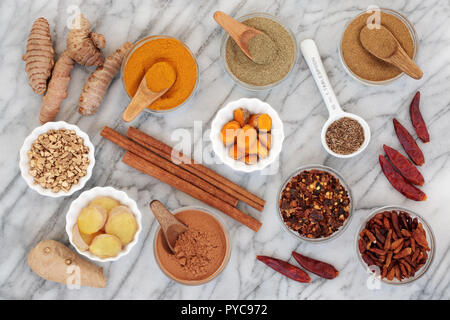 Spices for slimming with turmeric, cumin, ginger, chilli, cinnamon and gymnema sylvestre used to suppress appetite. Top view on marble background. Stock Photo