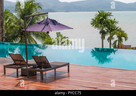 Beach chairs by the swimming pool with beautiful sea view Stock Photo